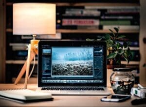 Gray laptop on a wooden desk next to a lamp