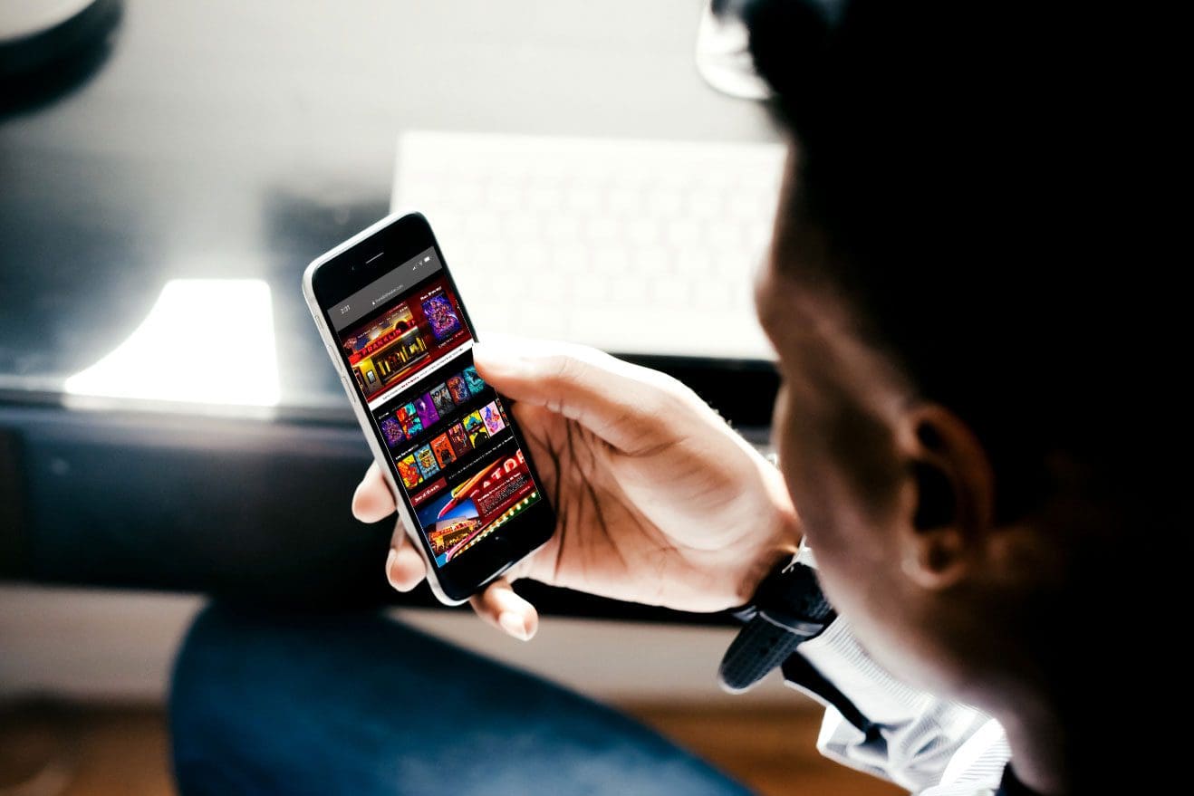 man scrolling through movie selections on his phone admiring a stunning website design and theme developed by a nashville company